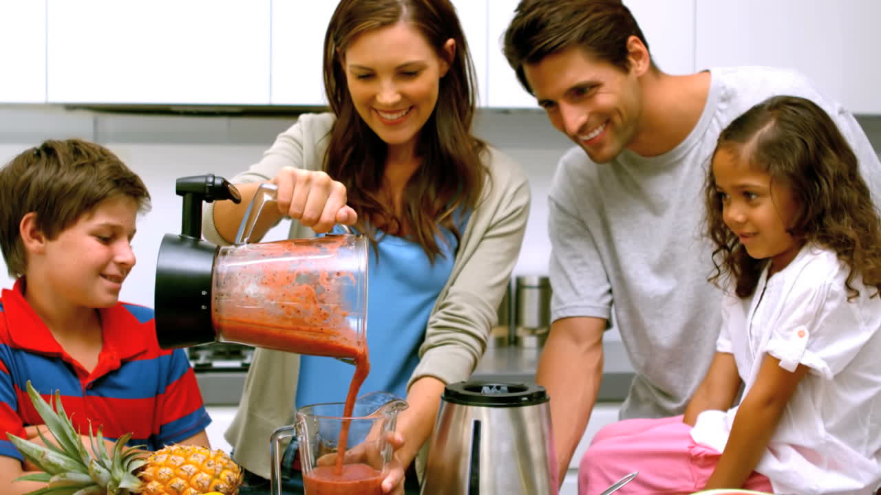 Donna sorridente con la famiglia che versa un frullato di frutta da un frullatore