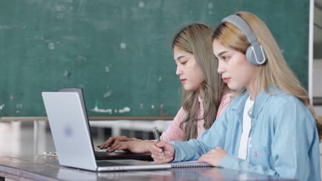 two asian girls student partners are working on a laptop help study together