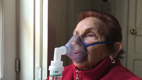 alejarse de la cara de una anciana caucásica usando mascarilla para la terapia de inhalación