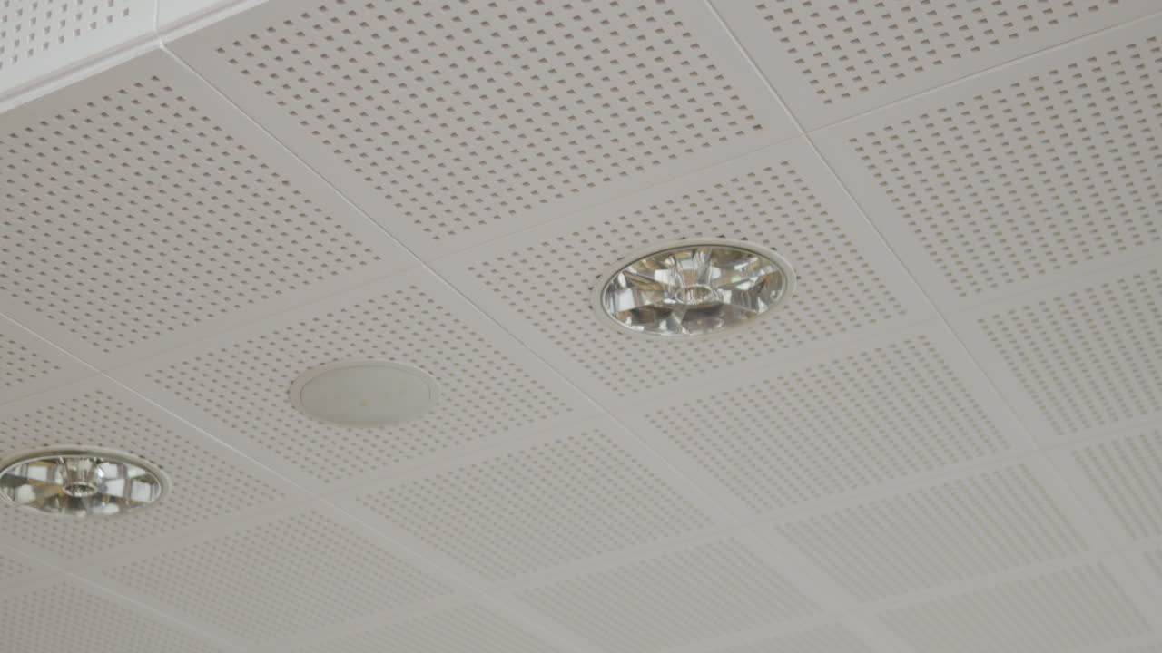 White cassette ceiling with visible small openings, recessed ceiling lights