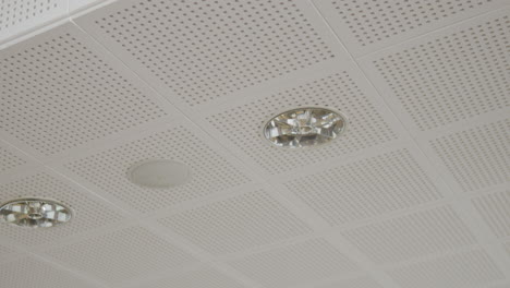 White-cassette-ceiling-with-visible-small-openings,-recessed-ceiling-lights