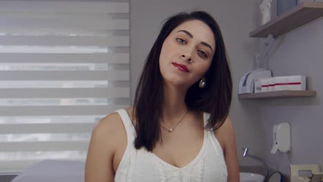 Woman-in-a-clinic-or-doctors-office-looks-and-smiles-up-as-someone-enters