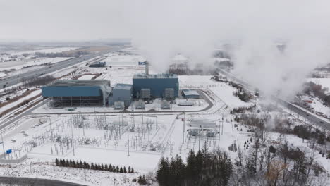 an industrial facility in winter, snow-covered landscape, with visible emissions and infrastructure, aerial view