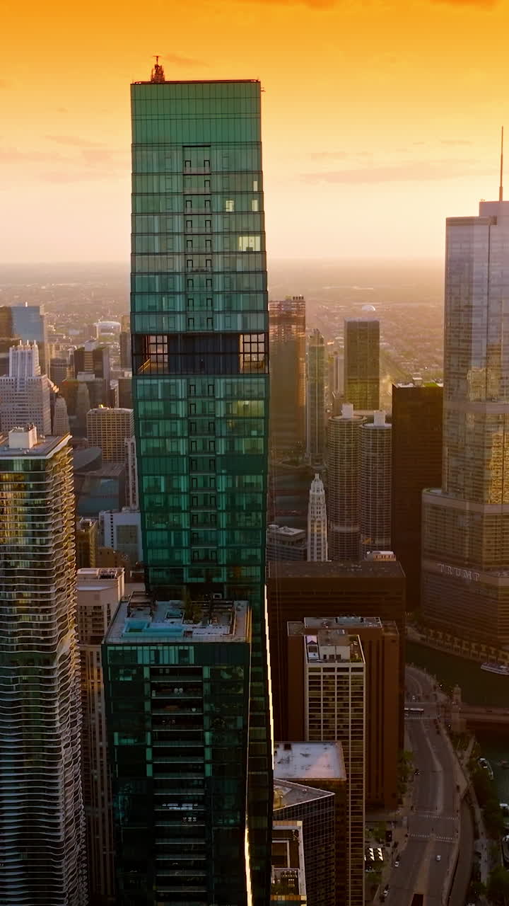 Chicago city aerial view at setting sun. Drone footage among the tops of skyscrapers in the rays of sun. Vertical video