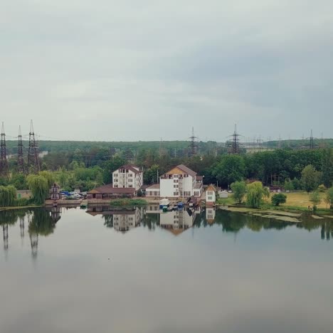 approximation to houses near the riverbank on the background of forest and high-voltage lines