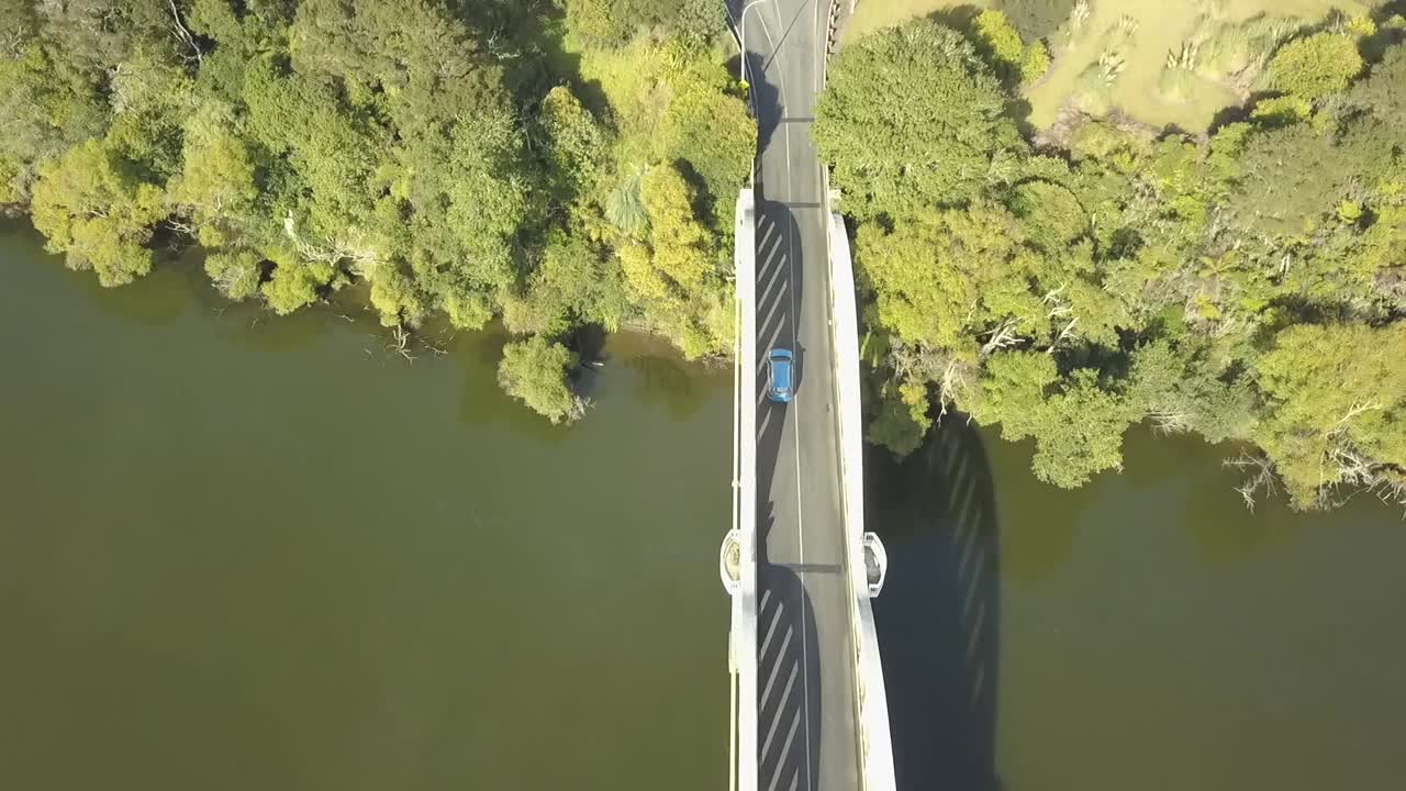 Birds eye drone aerial view of a car crossing a river on a white bridge in New Zealand.