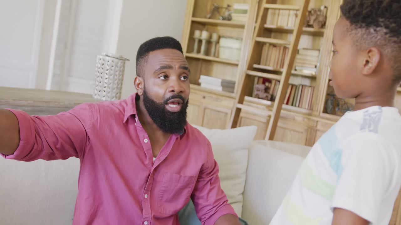 Sad african american father and son spending quality time together at home, in slow motion