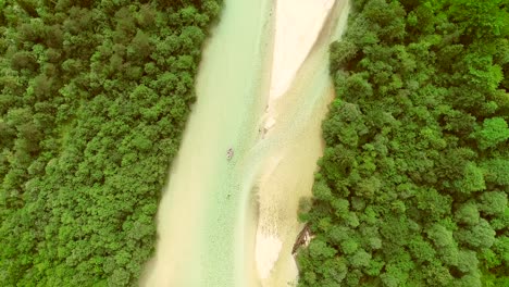 aerial view of adventurers doing rafting surrounded by a big green forest.