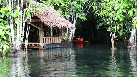 los kayakistas navegan por las aguas serenas por una cabaña rústica