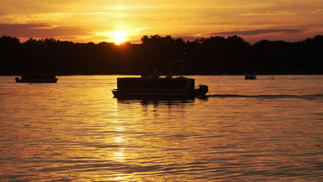 silhouette of boats enjoying a beautiful sunset reflecting on a peaceful lake