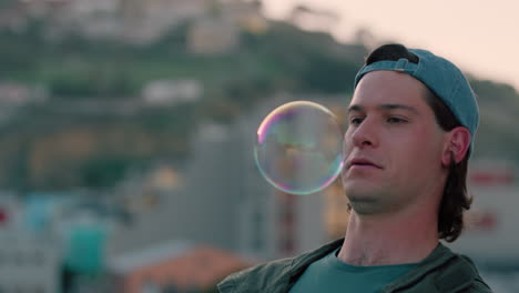 portrait attractive young man watching colorful soap bubbles floating enjoying playful fun