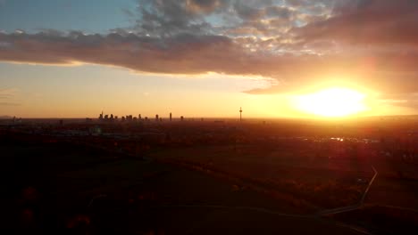 the silhouette of a distant skyline is visible against the setting sun