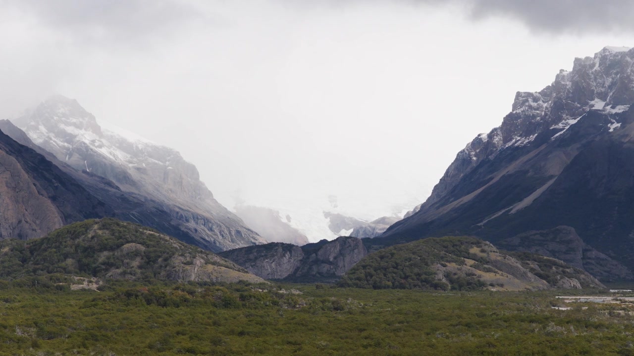 Valle glaciale che si estende verso il Campo di Ghiaccio Patagonico Meridionale vicino a El Chaltén, Santa Cruz, Argentina, aspre creste andine, terreno alpino e ghiacciai vallivi in avanzamento, ripresa aerea in avanti a velocità super ridotta.