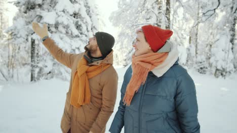 joyous couple walking through winter forest and chatting