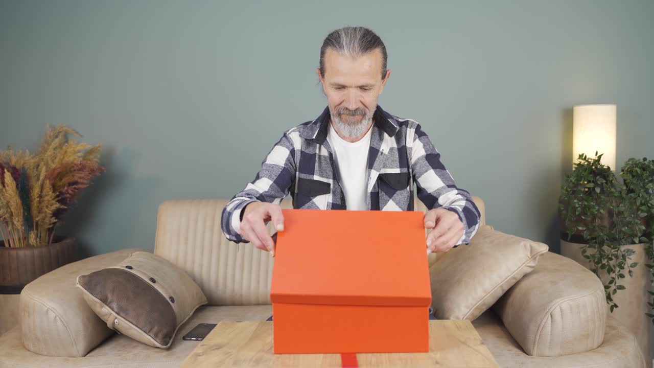 행복하고 즐거운 남자가 선물 패키지를 열고 있습니다.