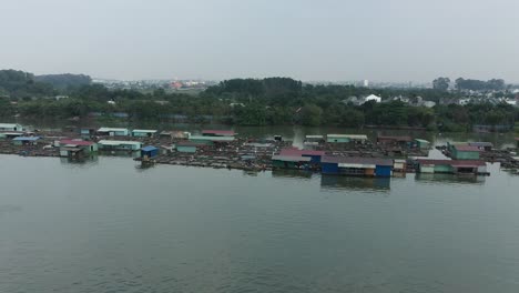 flying in over floating fish farming community in bien hoa on the dong nai river, vietnam on a sunny day