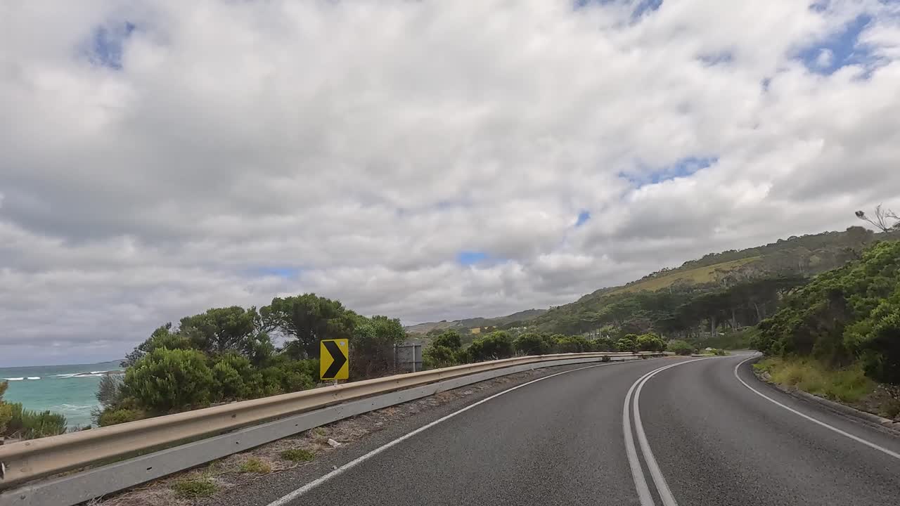 A 14-second drive showcasing coastal views and lush greenery along the Great Ocean Road under partly cloudy skies