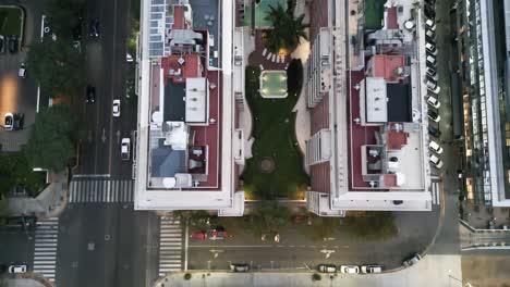 drone aéreo vuela sobre apartamentos altos de la ciudad de buenos aires con piscina, vista del techo entre calles con tráfico de automóviles y árboles