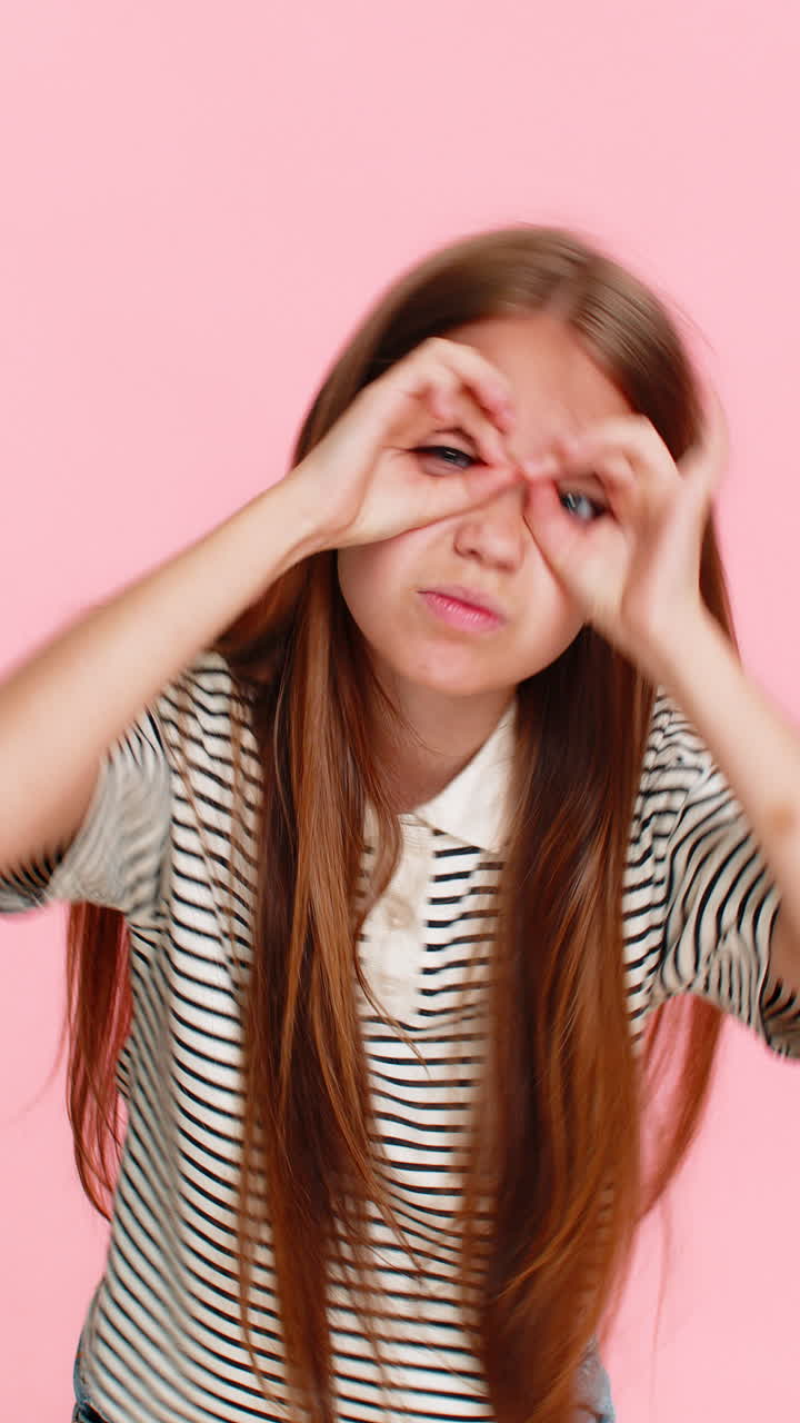 Child girl kid playfully forms glasses with fingers pretending to be smart see everything clearly