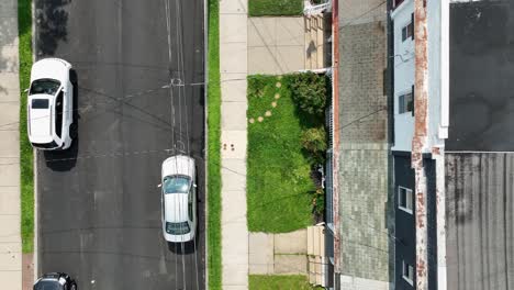 flag of america on facade of house in american town. sunny day with green grass in yard. aerial top down shot. electricity cable of ironman on street. cheap low housing area