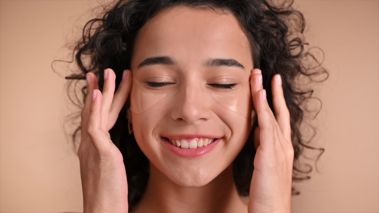 Uma jovem caucasiana sorridente colocando adesivos sob os olhos, olhando para a câmera. Câmera lenta