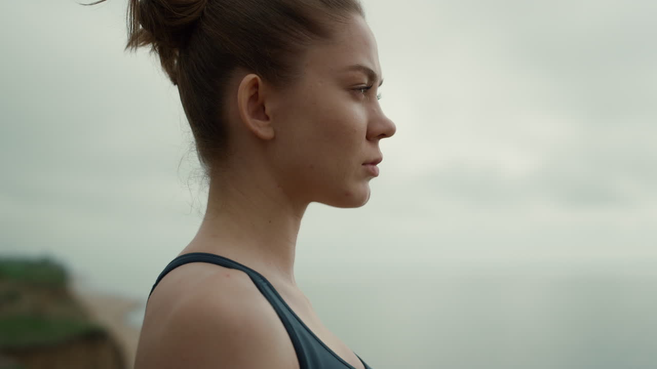 Sportswoman looking ahead standing beach closeup. Girl making breathing exercise