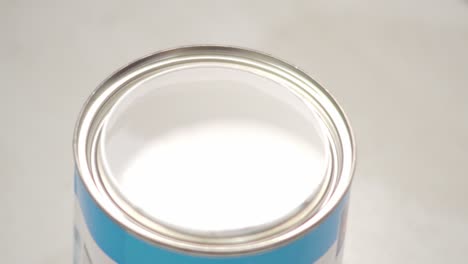 dipping a paint brush in a can of white paint close up