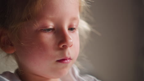 thoughtful little girl with pencil draws image in classroom