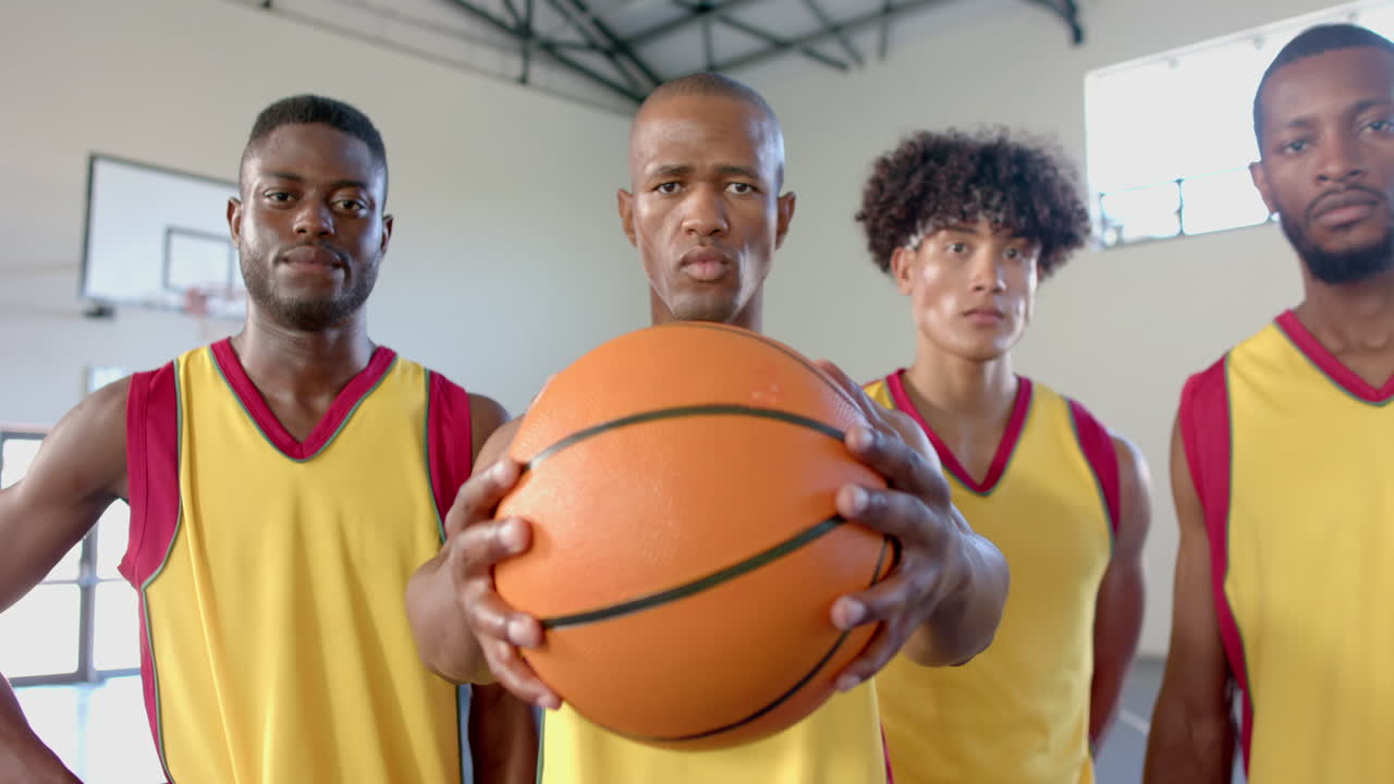 Equipo de baloncesto diverso posa con confianza en el gimnasio.