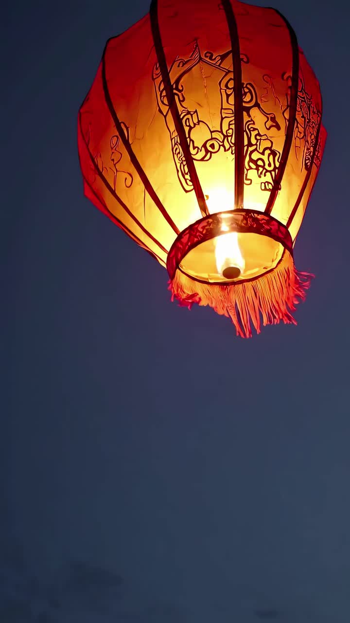 A low-angle shot of a glowing red lantern against a dark sky, capturing a serene and mystical