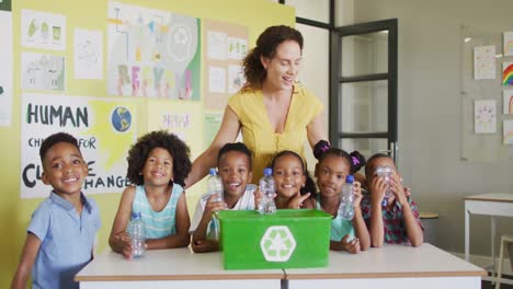 video of happy caucasian female teacher and class of diverse pupils studying ecology in classroom