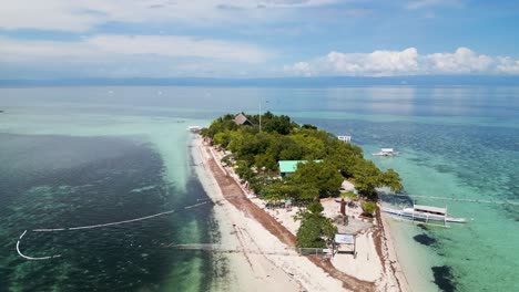 Kleine-Tropische-Strandinsel-Mit-Weißem-Sand,-Gebäuden-Und-Booten,-Die-In-Ufernähe-Geparkt-Sind