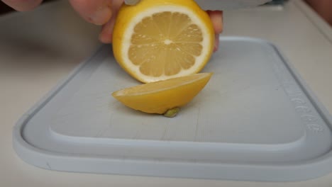 fresh lemon being sliced with a knife on a white cutting board, preparation for lemonade