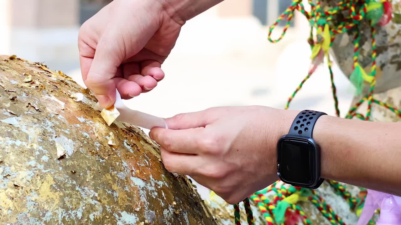 Close-up of hands carefully placing gold leaf on a textured, decorative object.