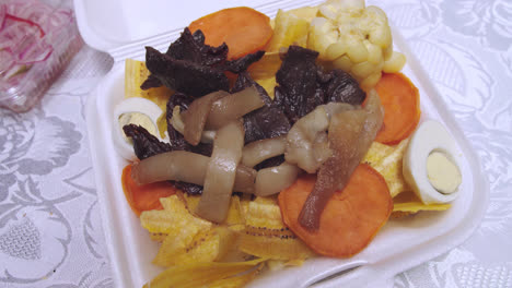 primer plano del plato peruano "carne seca" o biltong con chifles, camote y "maiz"