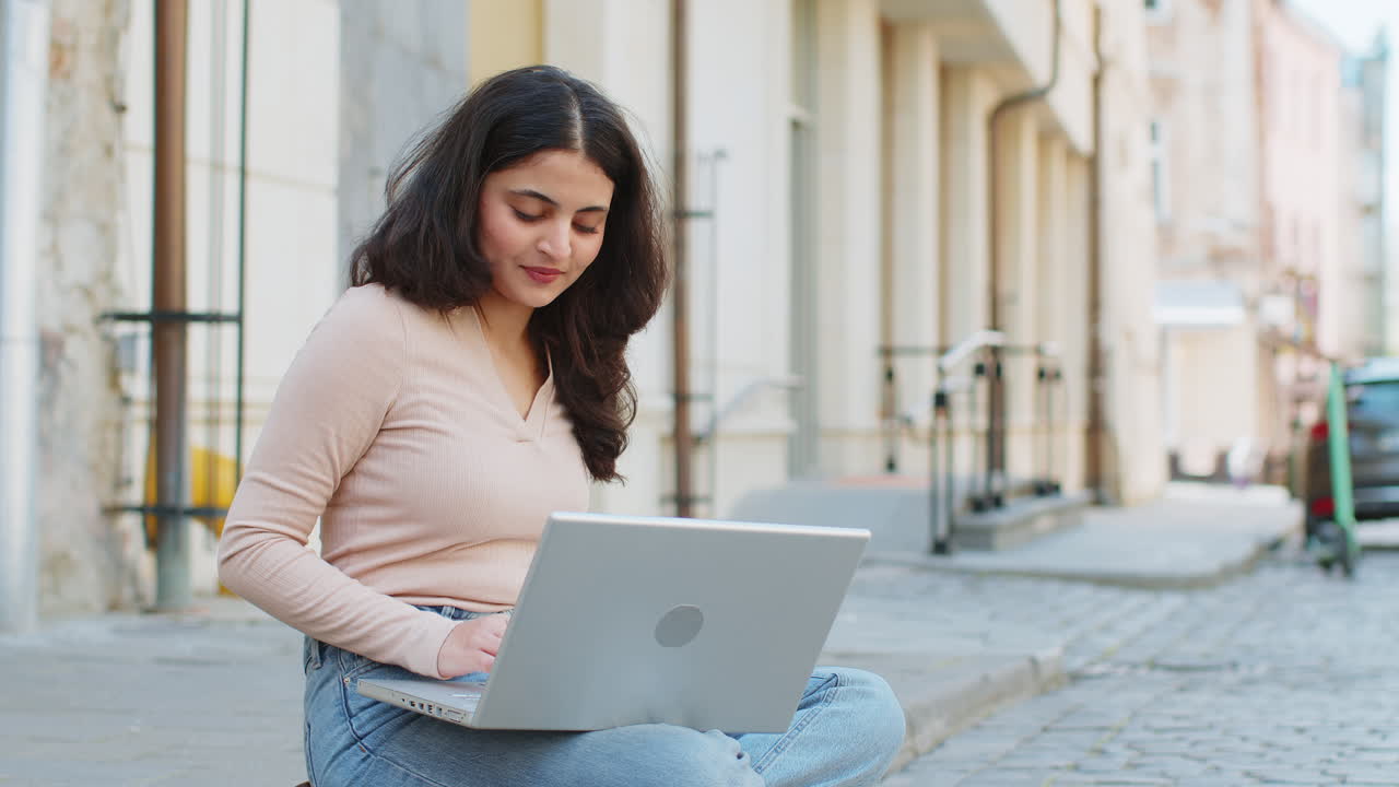 mujer freelance trabajando en línea trabajo remoto con portátil sentado en la calle de la ciudad navegando por el sitio web