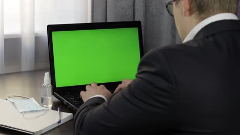 hombre tiene videoconferencia de llamada en portátil con pantalla verde. trabajo a distancia en línea