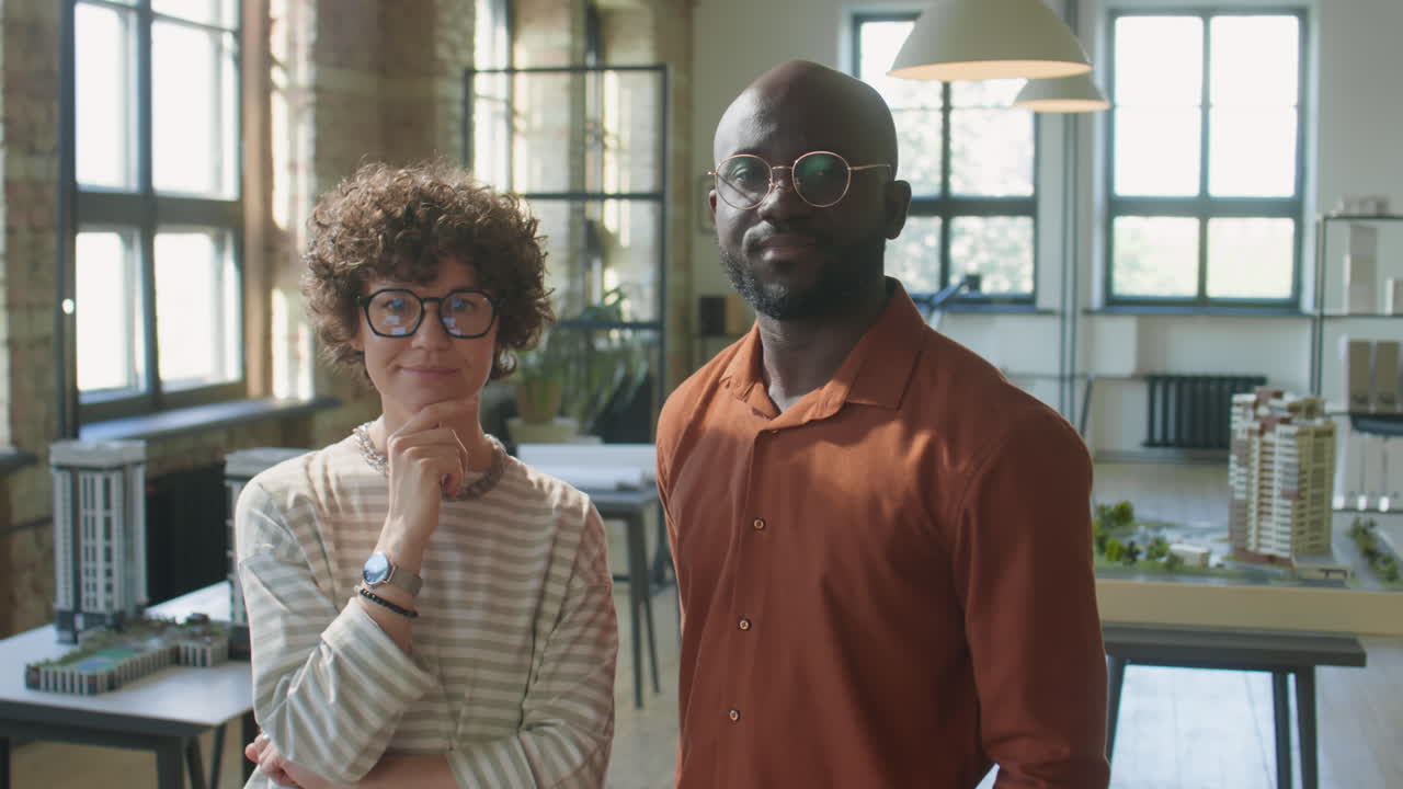 Two professional architects posing in their office with architectural models