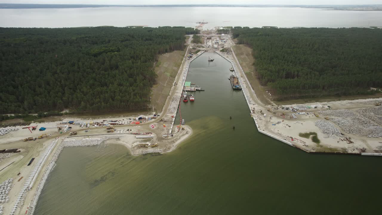 órbita aérea sobre el enorme sitio de construcción del canal marino a través de los bosques y la arquitectura marina moderna - vía fluvial de infraestructura a un puerto marítimo recién establecido