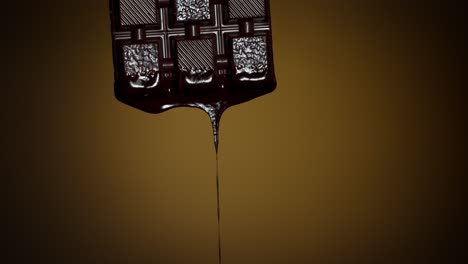 Slow-motion-of-chocolate-bar-with-melted-dark-chocolate-dripping-flowing-over-brown-background