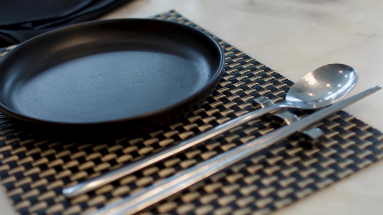 Person Setting Table with Plate and Metal Cutlery