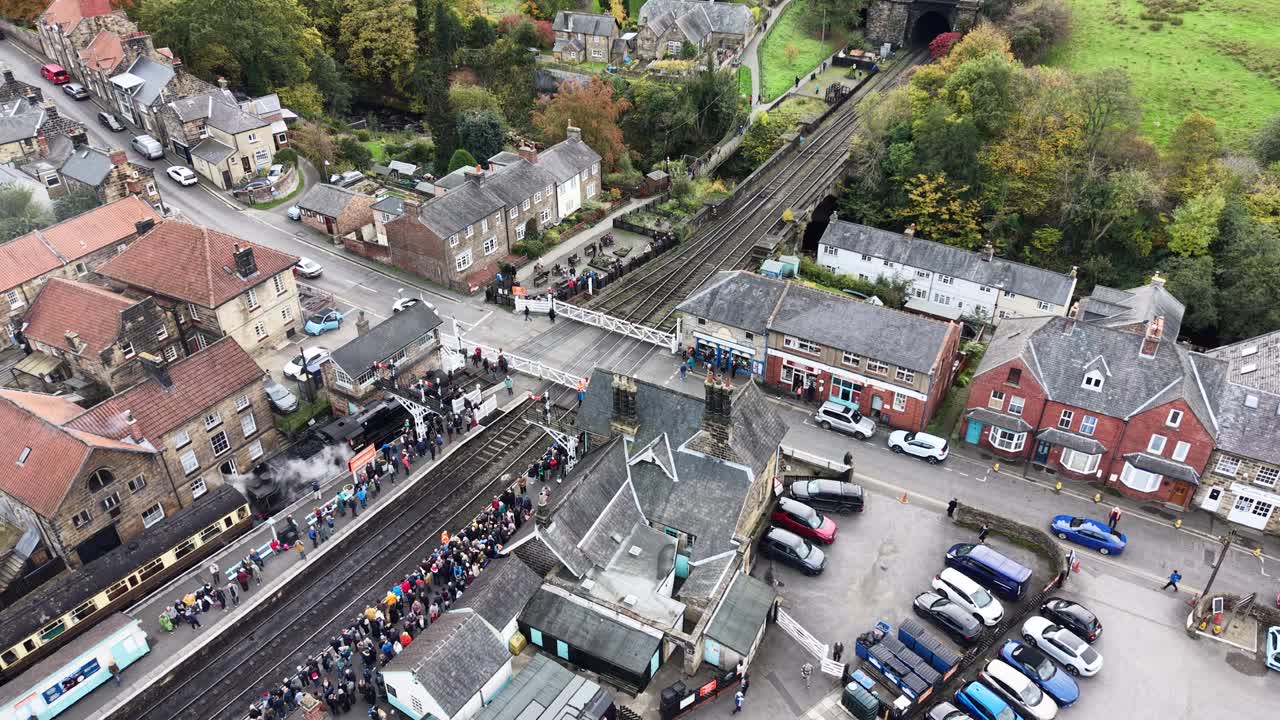 Vidéo aérienne par drone montrant la gare ferroviaire historique de Pickering avec des bâtiments historiques, des trains et des foules en automne dans le North Yorkshire, en Angleterre.