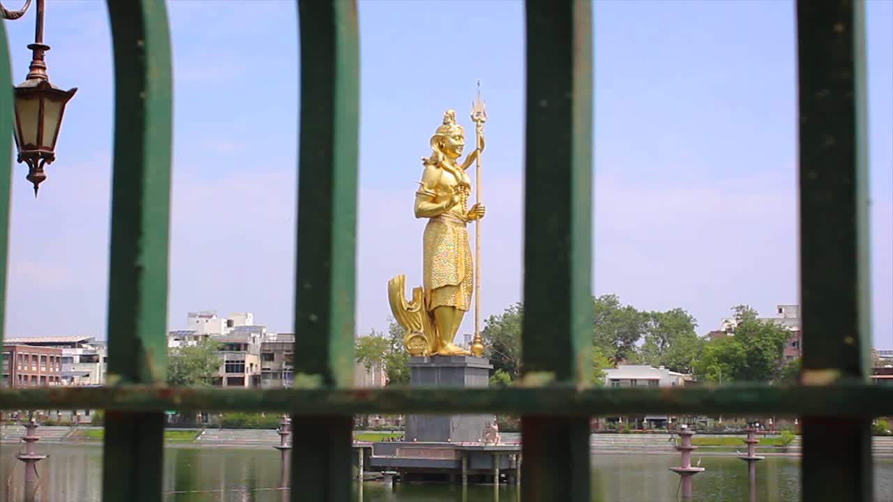 Majestic golden statue of Lord Shiva gracefully standing in serene Sursagar lake, Vadodara, Gujarat. Perfect for depicting Indian spirituality, landmarks and cultural beauty.