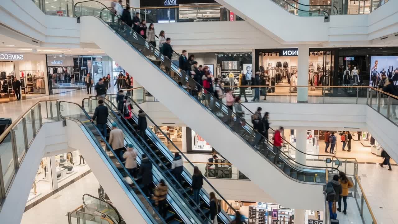 Crowds Navigate the Multi-Level Shopping Center Escalators, Showcasing a Busy Retail Environment with Shoppers Moving Between Floors and Various Stores in View