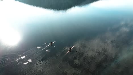 Un-Dron-Bajo-De-4k-Disparó-Sobre-Un-Lago-Invernal-En-Las-Montañas-Francesas-Con-Dos-Kayaks-Remando-Al-Sol