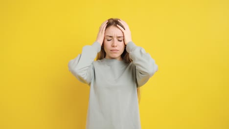 young woman suffering from strong headache on yellow background