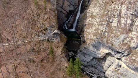 Luftaufnahme-Mit-Spektakulärem-Wasserfall,-Versteckt-Inmitten-Der-Steilen-Wände-Des-Braunen-Felsenbergs-In-Bohinj,-Slowenien