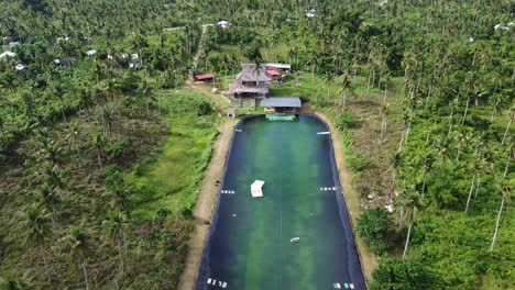 un jinete haciendo wakeboard en un lago artificial en el parque siargao wake en medio de la naturaleza tropical