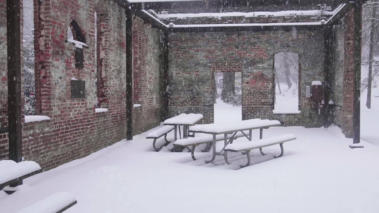 Snow covered picnic benches and brick building at Atlanta's Whittier Mill Village Park on January 10th, 2025.