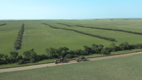 road leveling graders on rural road during summer in saskatchewan, canada